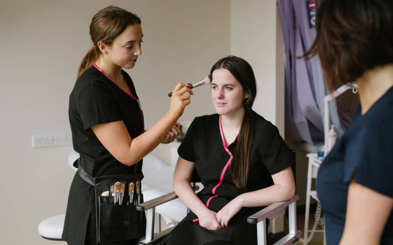 Beauty Therapy student practising make-up application on fellow student in college salon