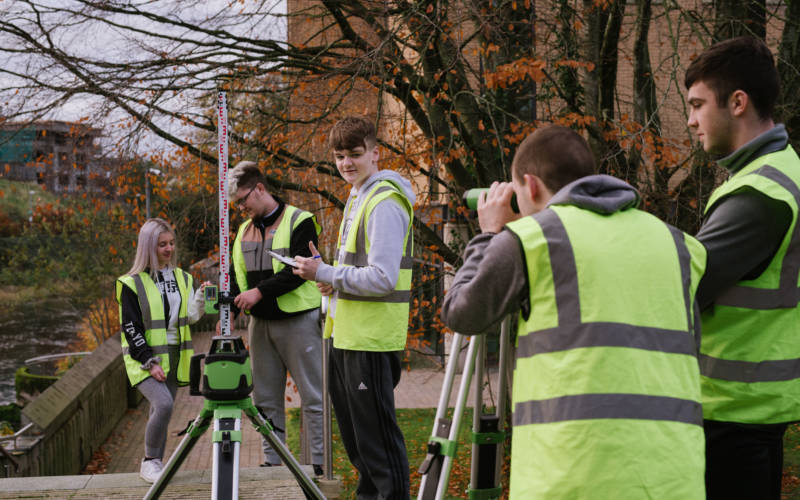 Group of construction students working outdoors wearing hi-vis jackets