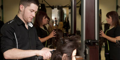 Hairdressing students at South West College working on clients' hair in college salon