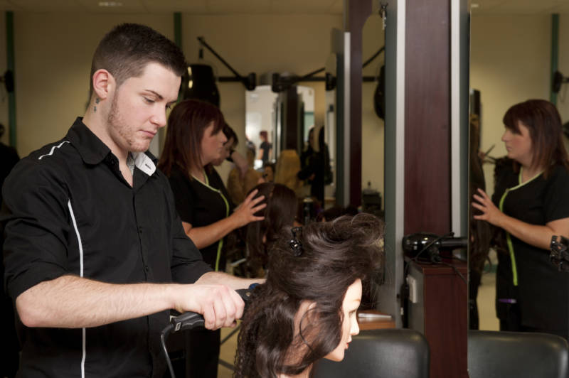 Hairdressing students at South West College working on clients' hair in college salon