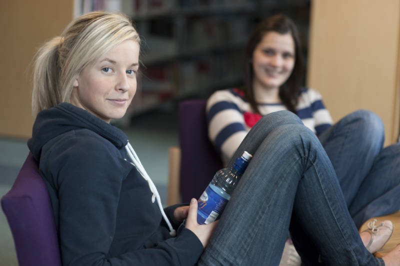 Two smiling students relaxing in one of the SWC campuses